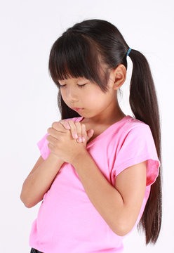 Portrait of a young girl praying against a white background