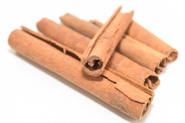 Cinnamon sticks stacked on white background.
