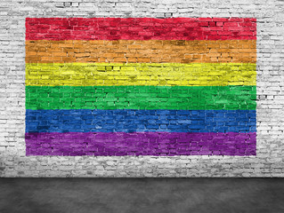 Rainbow flag painted over white brick wall