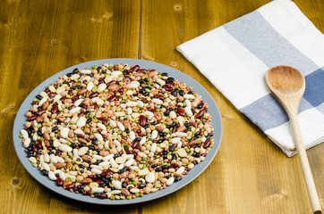 legumes in a dish on wood, with spoon, close up, background