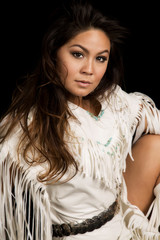 Native American woman in white outfit sit on black close looking