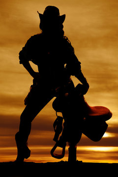 silhouette of cowgirl holding saddle straight on
