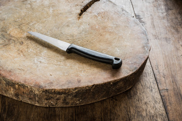 Empty chopping board with a sharp paring knife on a distressed g