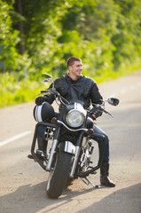 Fototapeta na wymiar Smiling happy biker in sitting unknown on big chopper bike on ro