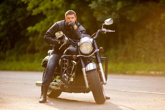 Fototapeta Smiling happy biker in sitting unknown on big chopper bike on ro