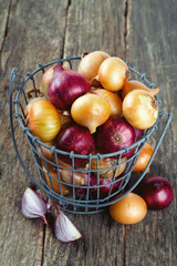 red and yellow onion in an iron basket on wooden surface