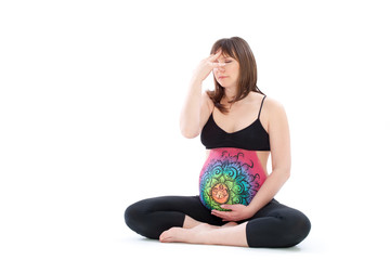 Woman with painted belly doing yoga exercise