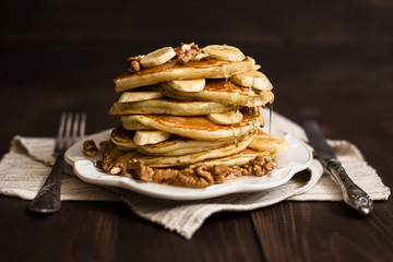Stack of pancakes with honey, banana and walnuts