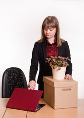 Dismissed girl in office with a box and flower closes laptop