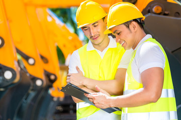 Asian engineer discussing plans on construction site