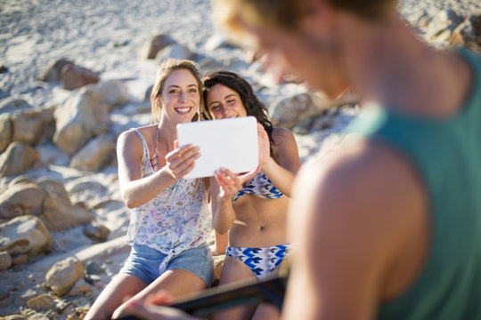 Girls taking a picture with a tablet of man playing acoustic guitar