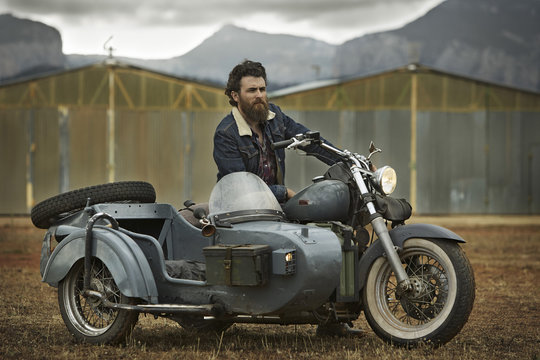 Man with full beard in motorcycle with sidecar