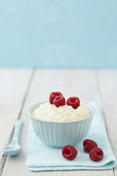 Bowl of milk rice pudding with raspberries on table