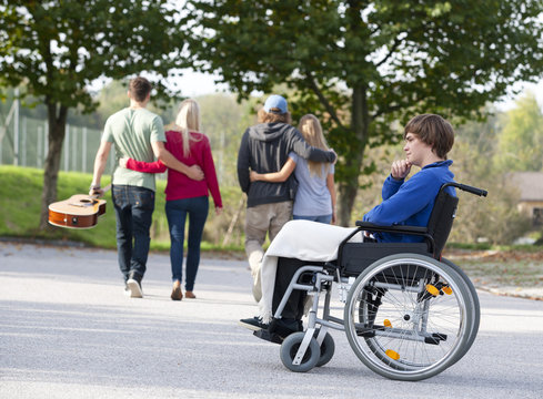 Two young couples arm in arm and young wheelchair user alone