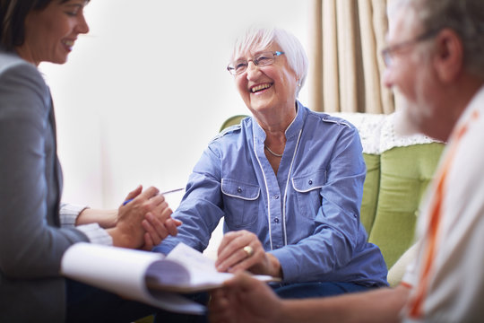 Smiling senior couple and woman with document