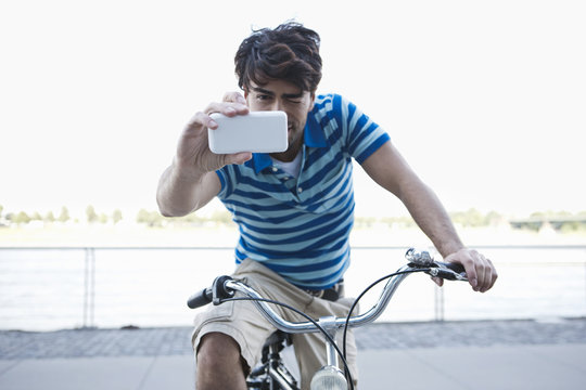 Germany, Cologne, Young man using cell phone