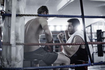 Boxer having a break with trainer in the corner of the boxing ring