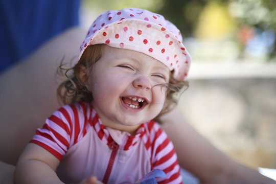 Portrait of laughing baby girl sitting on mother's lap