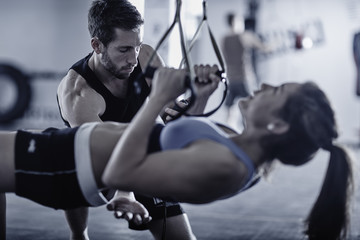 Fitness trainer keeping time with woman doing pull-ups