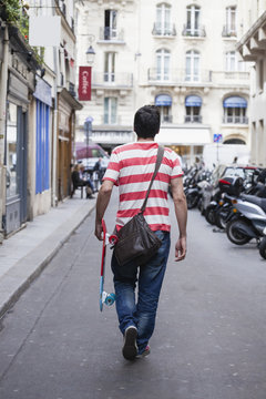 France, Paris, man with skateboard walking on a street