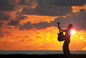 Guitarist playing guitar on the beach at sunset