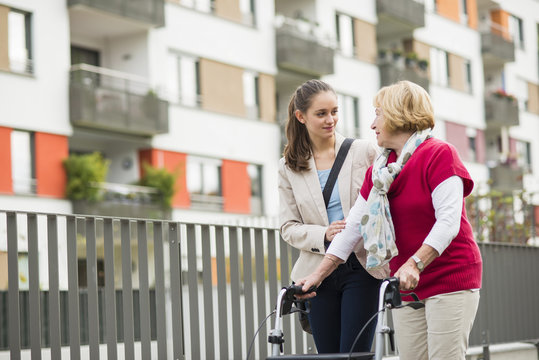 Granddaughter assisting her grandmother walking with wheeled walker