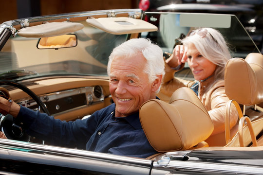 Portrait of a smiling senior couple sitting in a convertible car