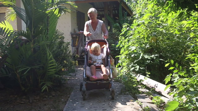grandmother carries blonde toddler in pram	