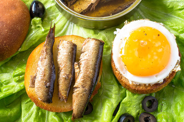 Burger with a fried egg and sardines