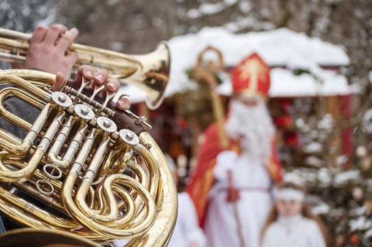 Musician playing horn with angel and Santa Claus in background