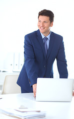 Business man or manager standing against his desk at the office