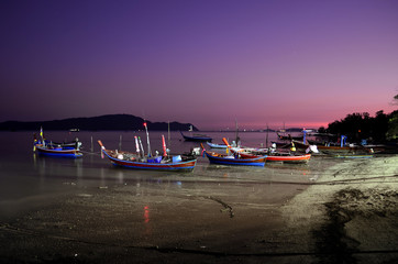 boats on the beach at night in phuket.