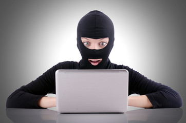 Hacker with computer wearing balaclava