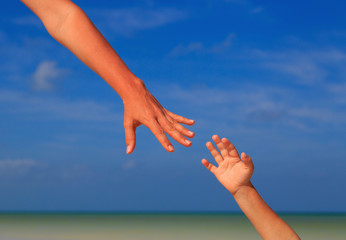 helping hand of mother and child on sky at the sea