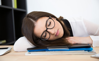 Young businesswoman sleeping at the table in office