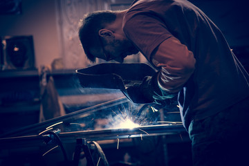 Employee at the factory welding steel using MIG MAG welder.