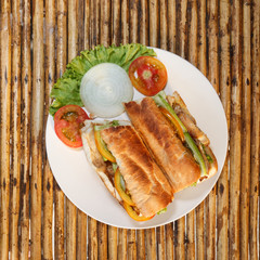 Chicken baguette on plate on bamboo table