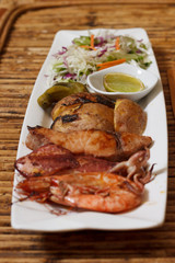 Seafood mix barbecue with salad on plate on bamboo table