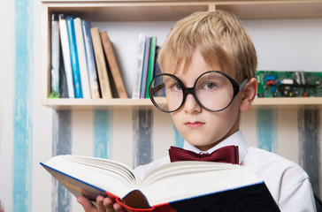 Portrait of a serious boy in bow tie with a book