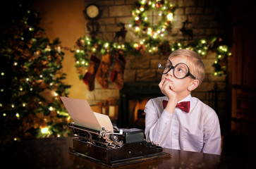 Boy typing a letter to Santa Claus on the typewriter