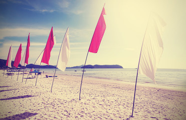 Retro filtered picture of flags on a beach.