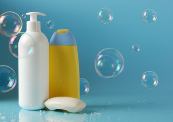 cosmetic bottles with soap bubbles over blue background