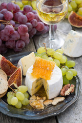 camembert with honey and fruit, snacks and wine on a plate