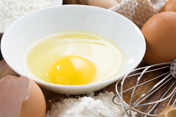 fresh egg in a bowl and ingredients for baking