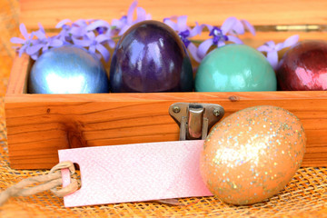 Colorful easter egg in wood box with blank paper tag.