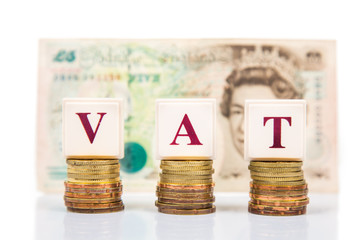 VAT concept with stack of coin and British Pound as backdrop - obrazy, fototapety, plakaty