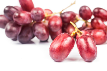 Close up of three pieces of red grape with a bunch in background