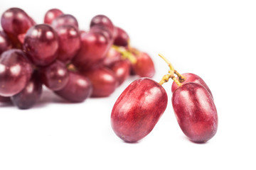Close up of three pieces of red grape with a bunch in background
