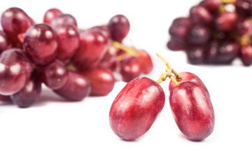 Close up of three pieces of red grape with a bunch in background