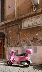 Naklejka premium Scooter rose dans une petite rue pavée romaine - Italie
